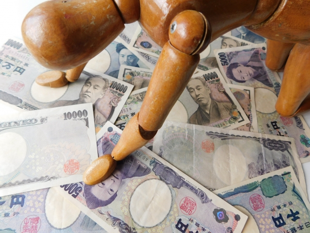 お金の上でうなだれる。松戸市で借金返済の相談は無料でできます